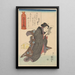 Woman in a black kimono with white stripes reading Sleeping Yellow Cat - Utagawa Kuniyoshi — framed artwork on a wall