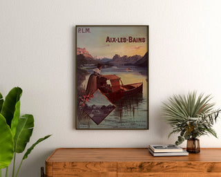 Vintage poster Aix‑les‑Bains, PLM group tickets, framed above a wooden dresser, flanked by plants.