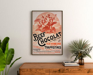Vintage poster Beef Chocolat, chocolaterie de la Drôme, framed above a wooden dresser between plants.
