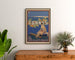 Vintage Cannes poster, Les Sports Élégants, framed above a wooden dresser between plants.