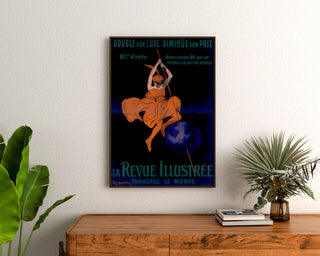 Vintage La Revue illustrée poster, framed above a wooden dresser between plants.