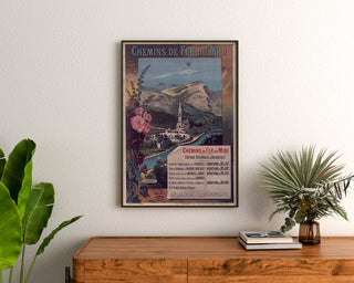 Vintage Lourdes seaside poster, framed above a wooden dresser, between plants.